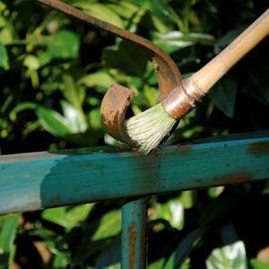 Owatrol oil being applied to a rusted metal fence